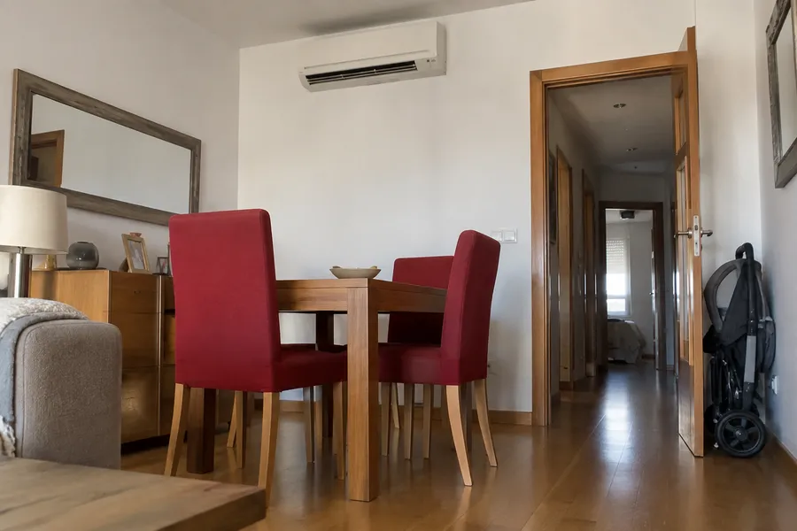 Aire acondicionado split sobre la puerta de un comedor con sillas rojas
